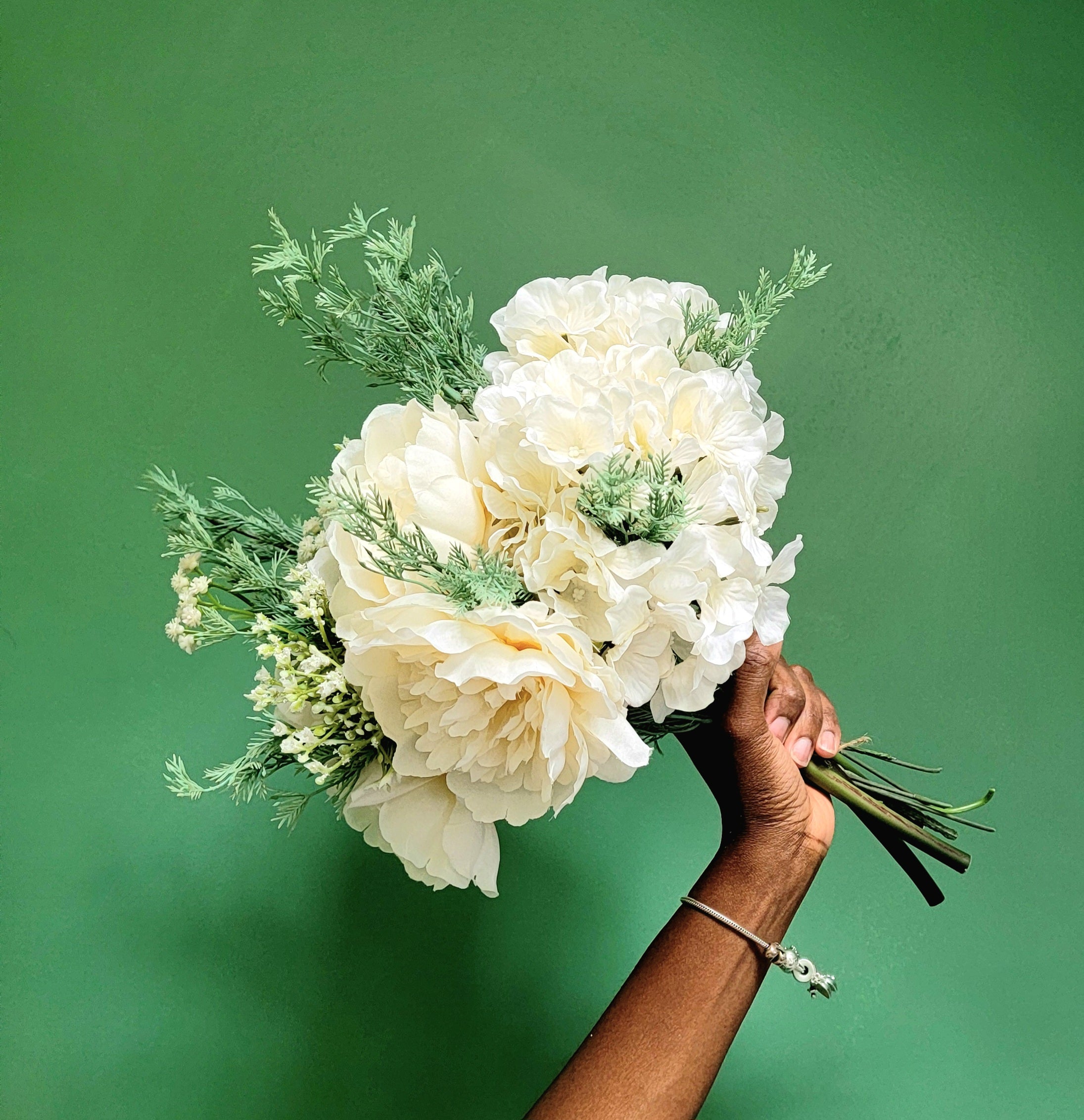 Bouquet of white flowers held against a green background
