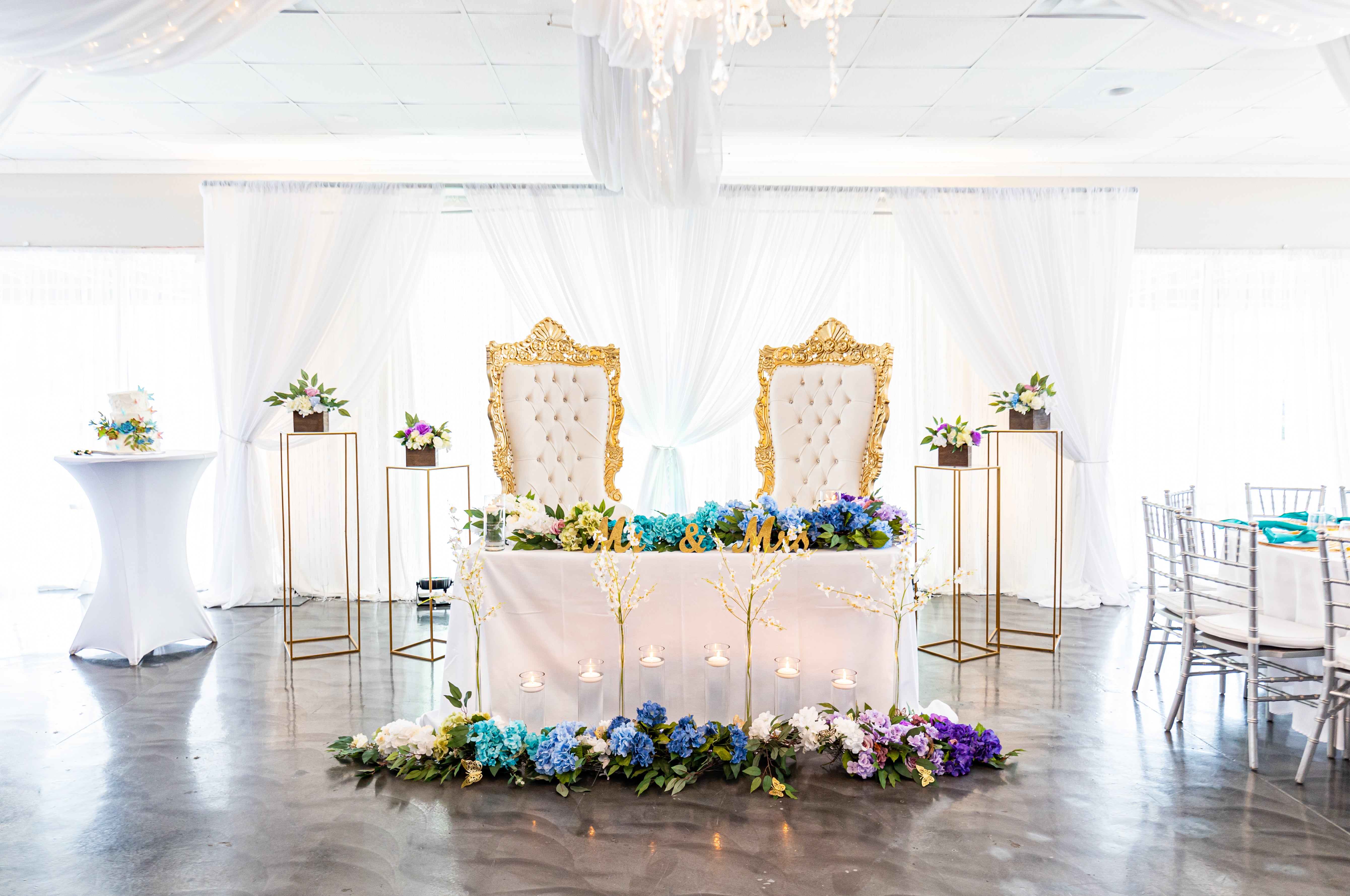 Decorated wedding setup with floral arrangements and chairs in a bright room.