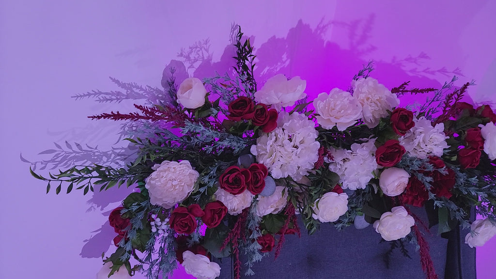 Burgundy, white and green floral piece for arches, sweetheart tables with roses, peonies, ranunculus, hydrangeas, spearmint and smilax. 