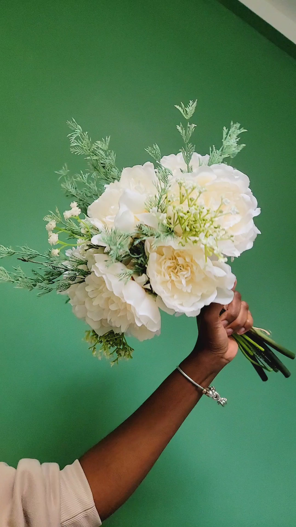 Bouquet of white flowers held by a person against a green background