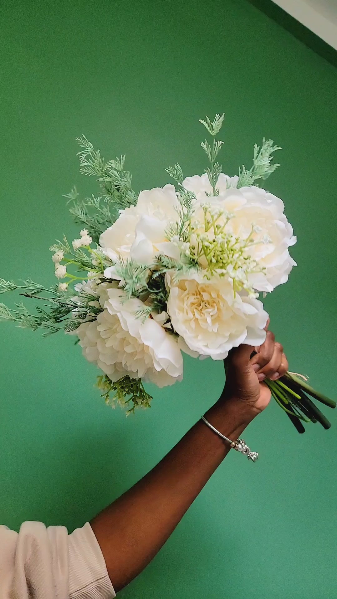 Bouquet of white flowers held by a person against a green background