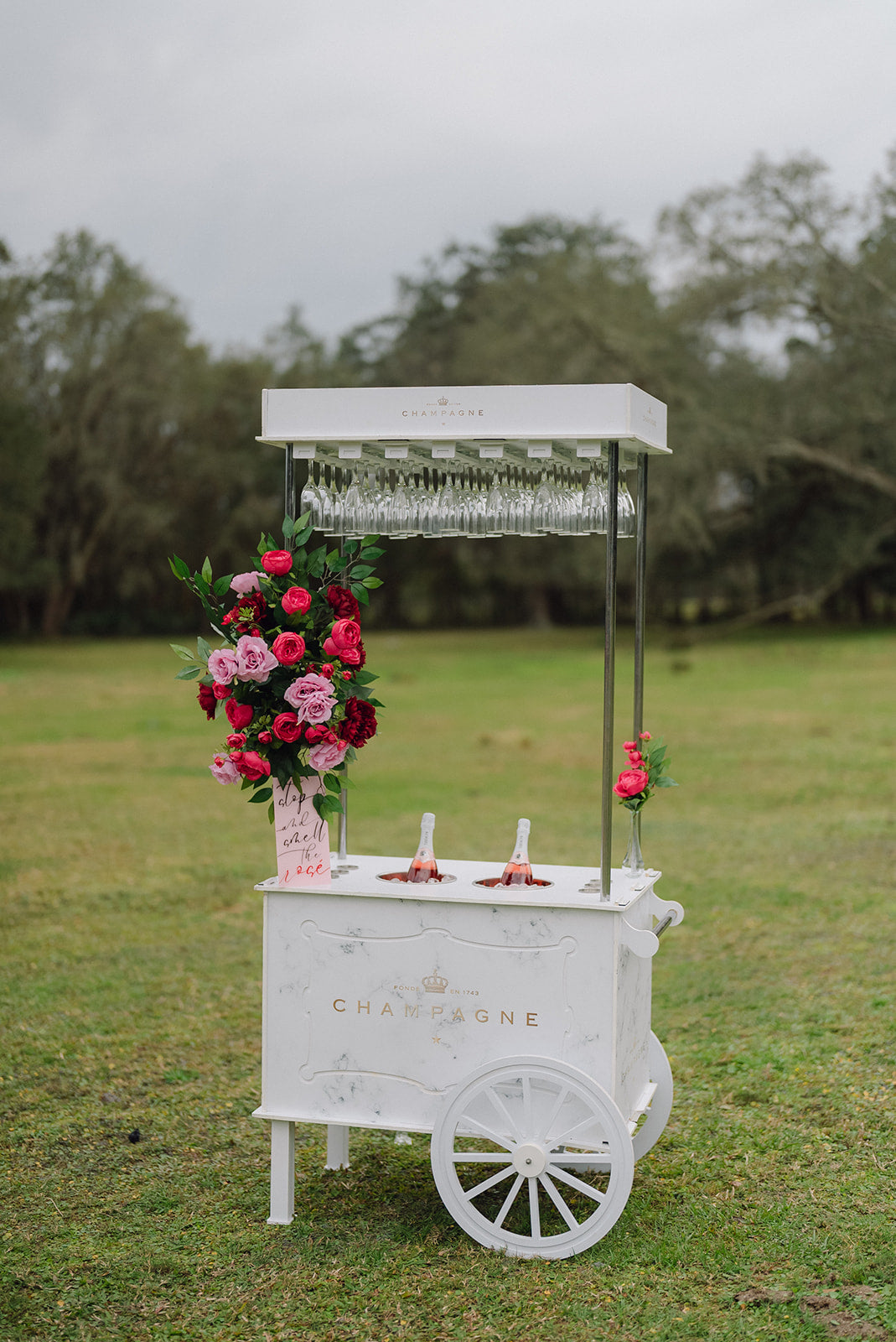 Decorative champagne cart with flowers on a grassy outdoor setting