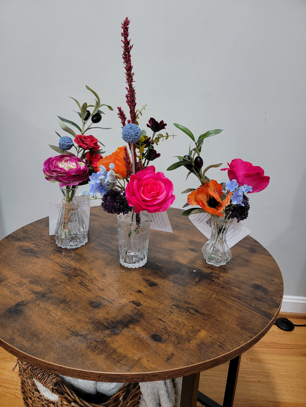 Colorful, gem tone flower arrangement on a wooden table with a plain background